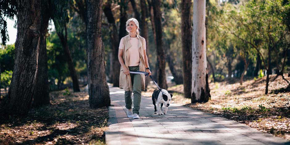Tutora caminando junto a su mascota. Los perros para adultos mayores también requieren pasear.